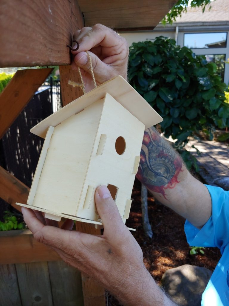 Image of arms and hands only hanging a bird house